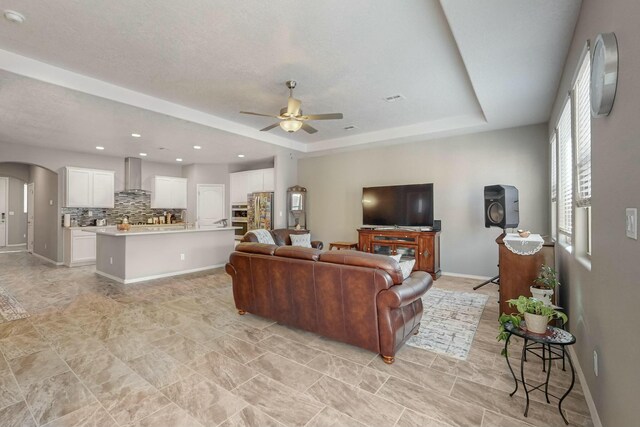 4017 Windy Rd NE, Rio Rancho, NM 87144 - living room with recessed lighting, arched walkways, baseboards, a ceiling fan, and a tray ceiling