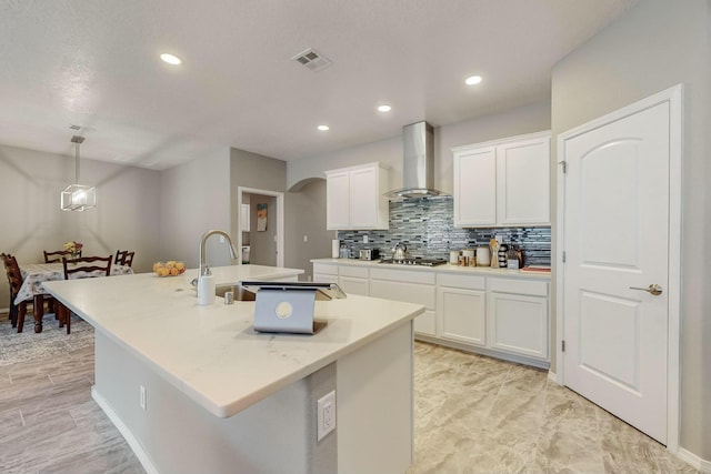 4017 Windy Rd NE, Rio Rancho, NM 87144 - kitchen featuring tasteful backsplash, white cabinets, visible vents, wall chimney exhaust hood, and a kitchen island with sink