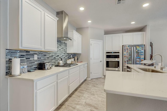 4017 Windy Rd NE, Rio Rancho, NM 87144 - kitchen featuring appliances with stainless steel finishes, backsplash, a sink, white cabinetry, and wall chimney exhaust hood