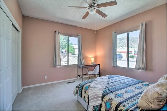 carpeted bedroom with baseboards, a textured ceiling, visible vents, and a closet