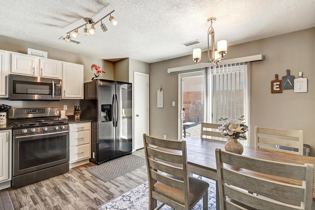 kitchen featuring dark countertops, visible vents, stainless steel appliances, and a chandelier
