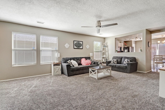 carpeted living room with a textured ceiling, visible vents, baseboards, and ceiling fan with notable chandelier
