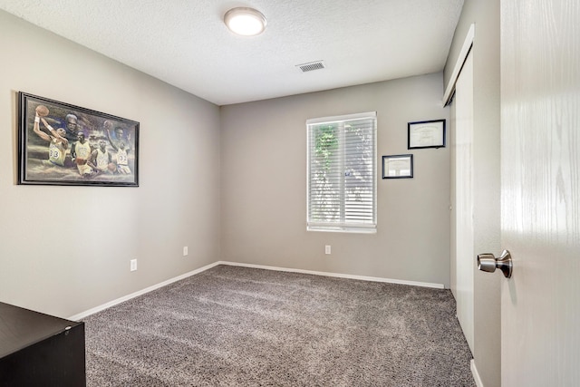 spare room featuring a textured ceiling, visible vents, carpet, and baseboards