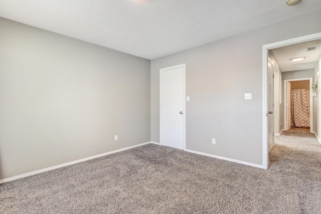 unfurnished bedroom featuring visible vents, carpet flooring, a textured ceiling, and baseboards