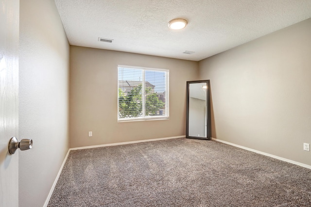 spare room featuring a textured ceiling, visible vents, baseboards, and carpet floors