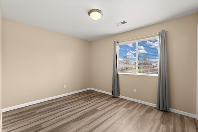 unfurnished room featuring baseboards, visible vents, and light wood-style flooring