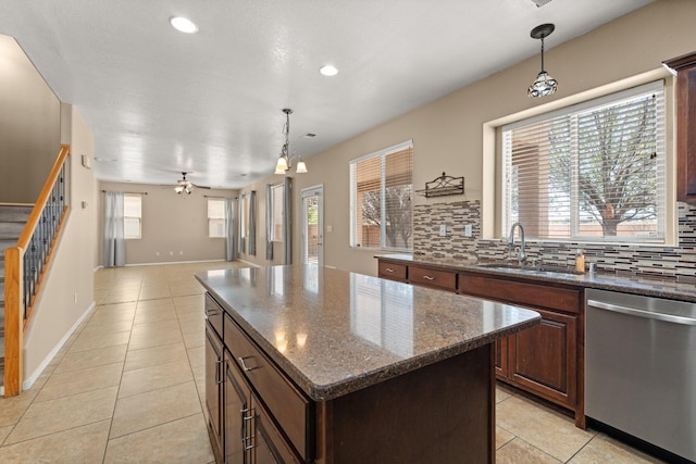 kitchen featuring light tile patterned floors, decorative backsplash, stainless steel dishwasher, a sink, and open floor plan
