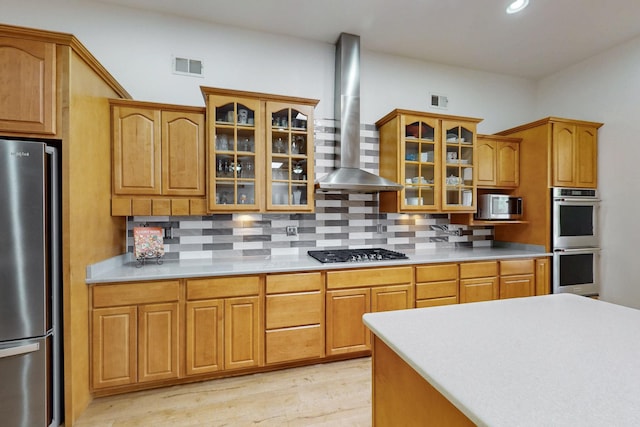630 Barnett Rd, Bosque Farms, NM 87068 - kitchen featuring appliances with stainless steel finishes, wall chimney range hood, backsplash, light countertops, and light wood-style floors