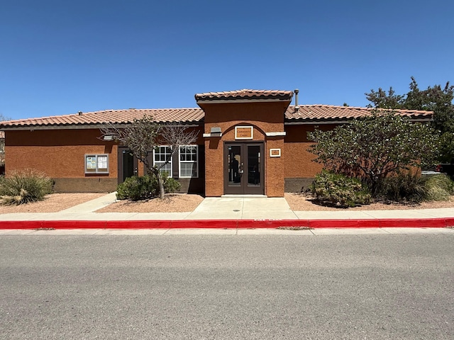 mediterranean / spanish-style home featuring stucco siding, a tiled roof, and french doors