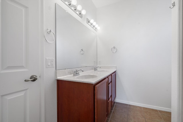full bath featuring baseboards, tile patterned flooring, double vanity, and a sink