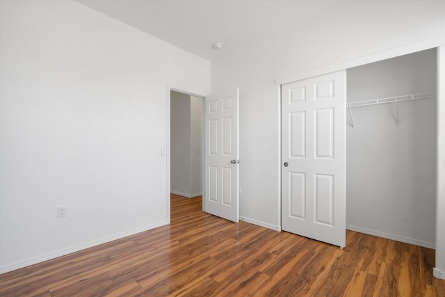 unfurnished bedroom featuring a closet, wood finished floors, and baseboards