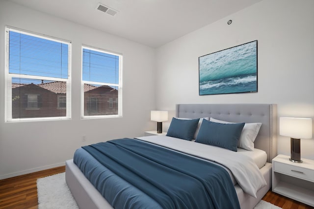 bedroom featuring wood finished floors, visible vents, and baseboards