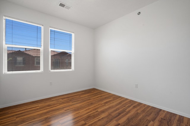 spare room with baseboards, visible vents, and wood finished floors