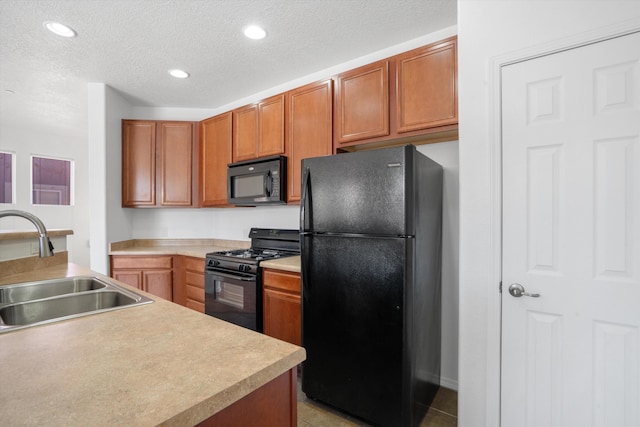 kitchen with brown cabinetry, black appliances, a textured ceiling, and a sink