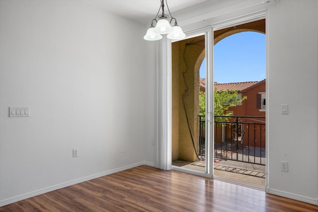 interior space featuring wood finished floors, a notable chandelier, and baseboards