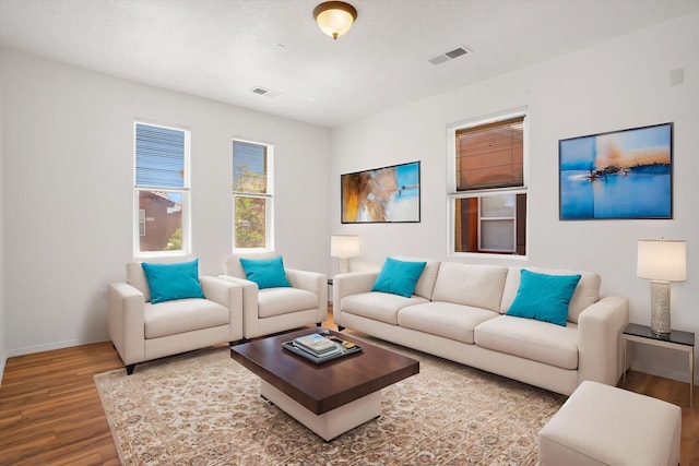 living room with baseboards, visible vents, and wood finished floors