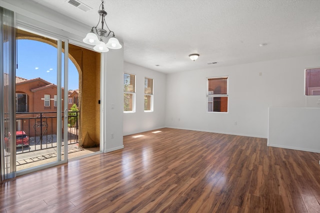 spare room with wood finished floors, visible vents, a notable chandelier, and baseboards