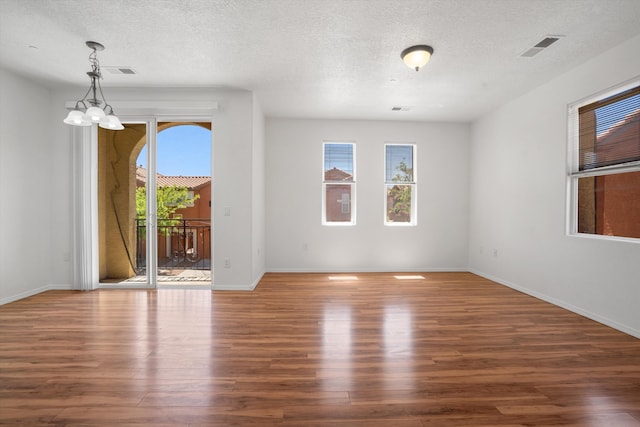 spare room featuring baseboards, wood finished floors, and a textured ceiling