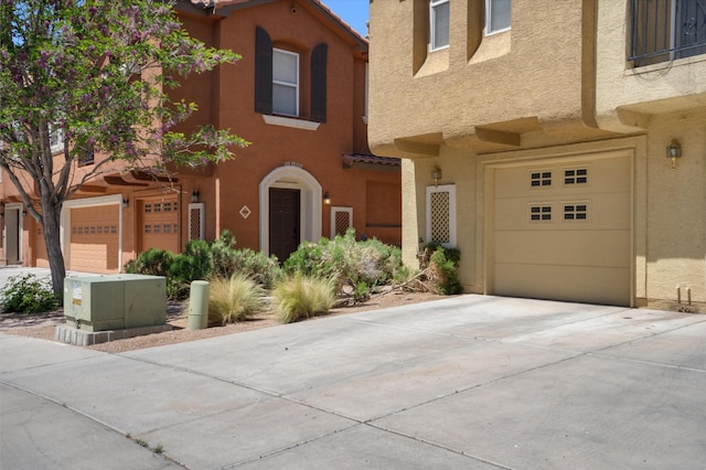 townhome / multi-family property with stucco siding, concrete driveway, and an attached garage