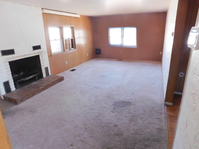 unfurnished living room featuring a fireplace, visible vents, and carpet floors