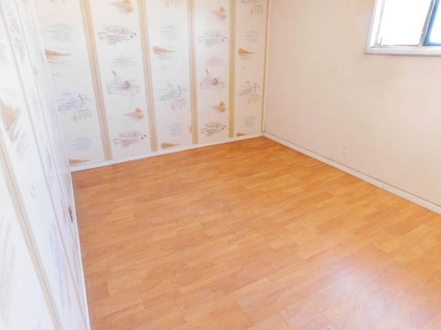 unfurnished room with light wood finished floors and baseboards