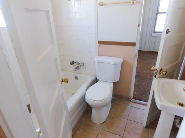 bathroom with toilet, baseboards, a sink, tile patterned floors, and bathing tub / shower combination