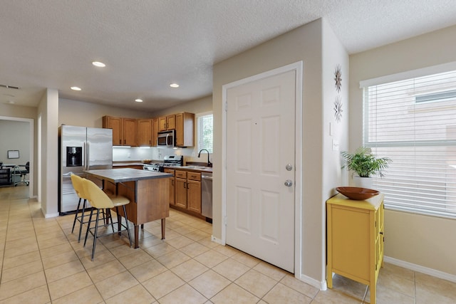 kitchen featuring a sink, a textured ceiling, a breakfast bar area, and stainless steel appliances