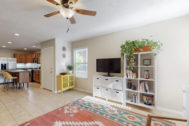 living area with ceiling fan, a textured ceiling, recessed lighting, baseboards, and light tile patterned floors