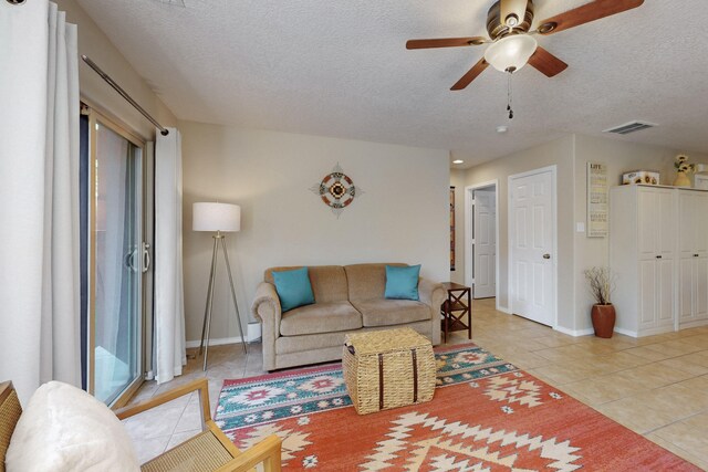 living room featuring light tile patterned floors, ceiling fan, a textured ceiling, and visible vents