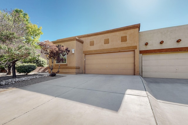 adobe home with an attached garage, stucco siding, and concrete driveway