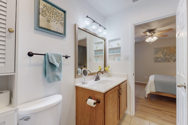 ensuite bathroom with connected bathroom, ceiling fan, tile patterned flooring, vanity, and toilet
