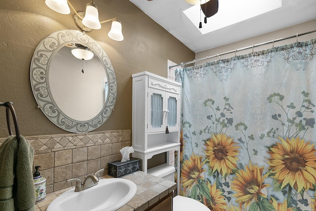 7 Wildwood Ln, Peralta, NM 87042 - full bath with vanity, ceiling fan, toilet, a textured wall, and a skylight