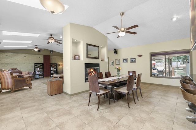7 Wildwood Ln, Peralta, NM 87042 - dining area with a glass covered fireplace, a ceiling fan, light tile patterned floors, and vaulted ceiling with skylight