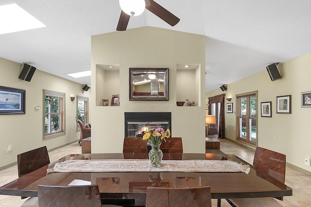 7 Wildwood Ln, Peralta, NM 87042 - dining area with lofted ceiling with skylight, a multi sided fireplace, baseboards, a ceiling fan, and light tile patterned flooring
