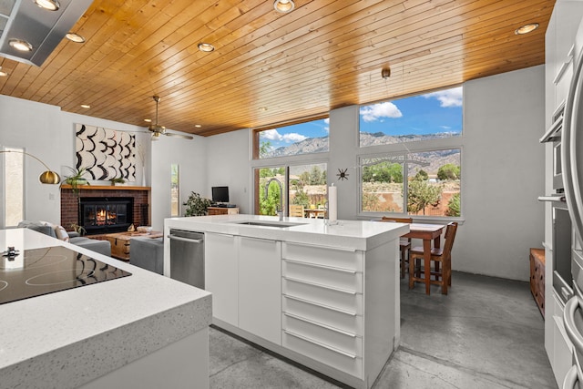 kitchen featuring open shelves, a sink, a brick fireplace, concrete floors, and wood ceiling