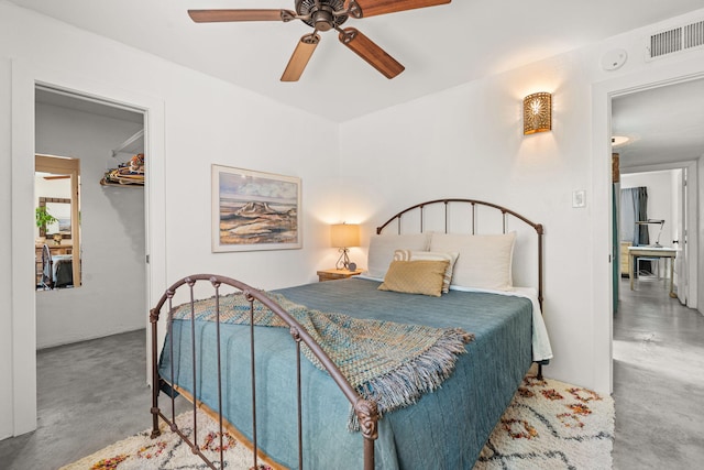 bedroom featuring a walk in closet, ceiling fan, visible vents, finished concrete flooring, and a closet