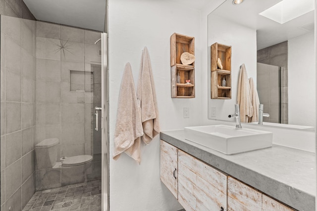 bathroom featuring toilet, a skylight, a shower stall, and vanity