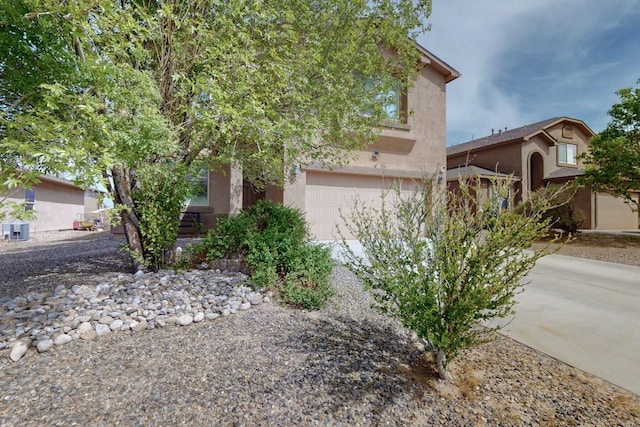 view of front facade with an attached garage, driveway, central AC, and stucco siding