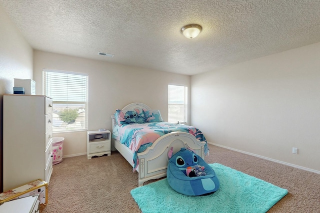 bedroom featuring a textured ceiling, visible vents, baseboards, and carpet floors