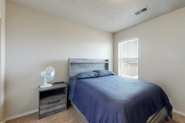 carpeted bedroom featuring a textured ceiling, visible vents, and baseboards