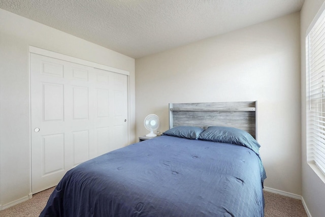 carpeted bedroom featuring a closet, a textured ceiling, and baseboards