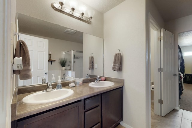 bathroom featuring tile patterned floors, double vanity, a stall shower, and a sink