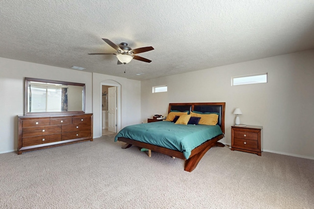 carpeted bedroom with visible vents, arched walkways, a textured ceiling, and multiple windows