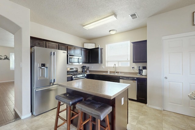 kitchen with a sink, stainless steel appliances, a wealth of natural light, visible vents, and a kitchen island