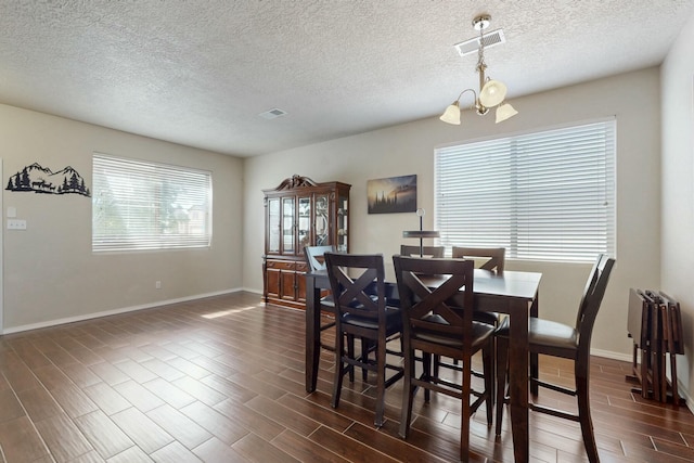 dining area featuring a textured ceiling, visible vents, baseboards, an inviting chandelier, and dark wood finished floors