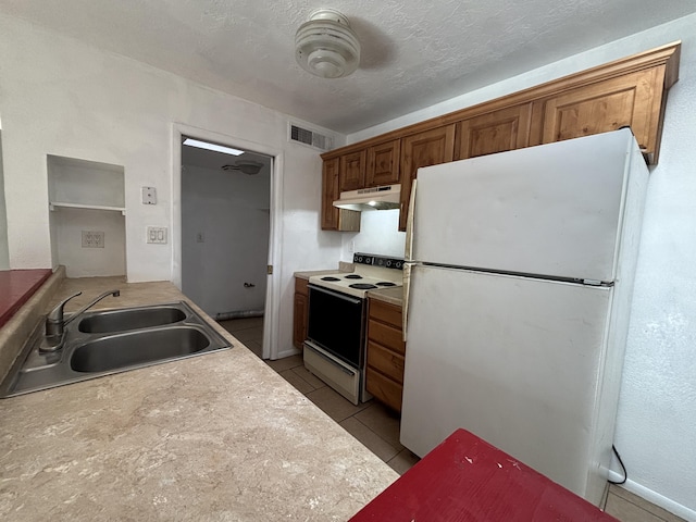 kitchen featuring a sink, visible vents, light countertops, under cabinet range hood, and white appliances
