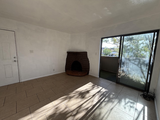 unfurnished living room with a brick fireplace, tile patterned flooring, and baseboards