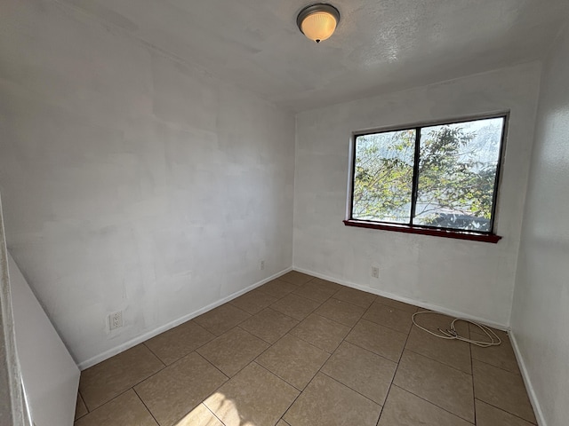 tiled empty room featuring baseboards