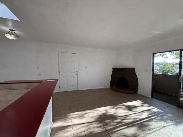 unfurnished living room featuring a skylight, baseboards, tile patterned floors, and a fireplace