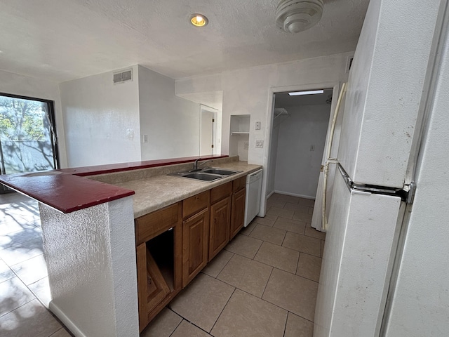 kitchen with light tile patterned floors, visible vents, white appliances, and a sink